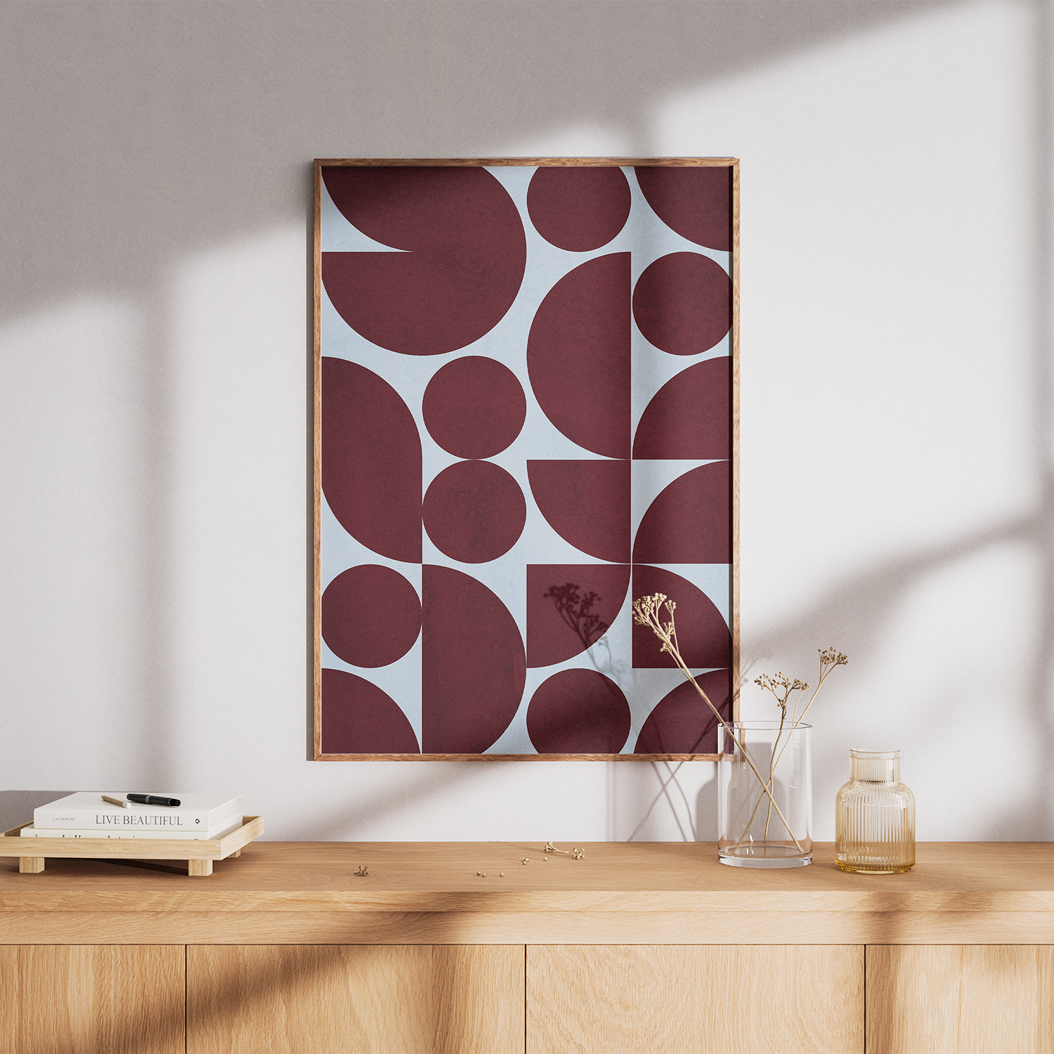 Framed abstract art on a wall above a wooden surface with decor items.